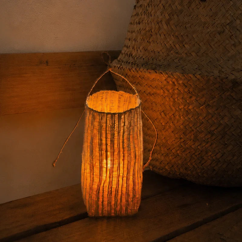 Vejle lantern lit beside a woven basket