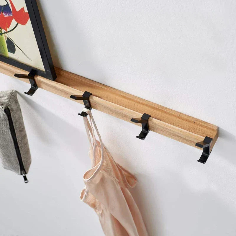 Coat rack on a white wall holding a towel and a camisole