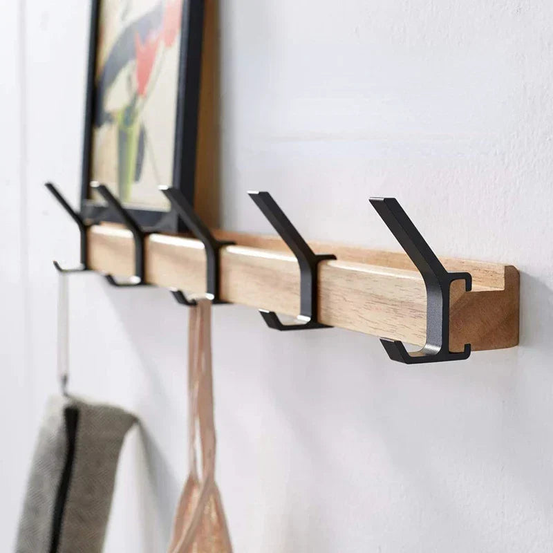 Angled view of the coat rack with black double hooks holding a towel and a top