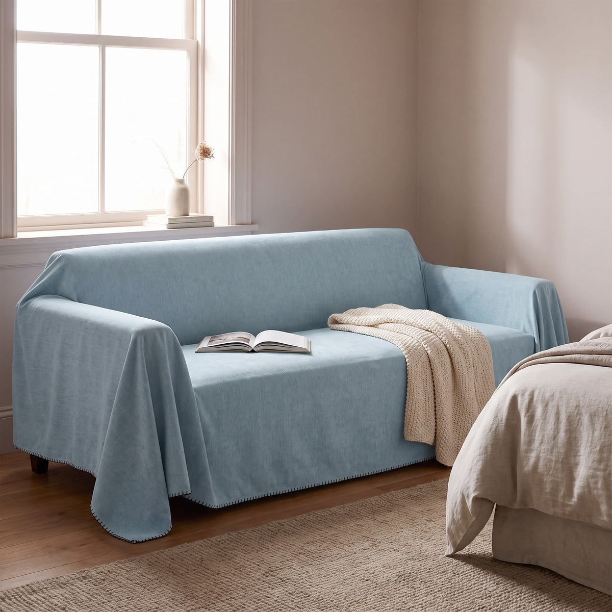 Waterproof sofa cover in light blue over a sofa in a bedroom