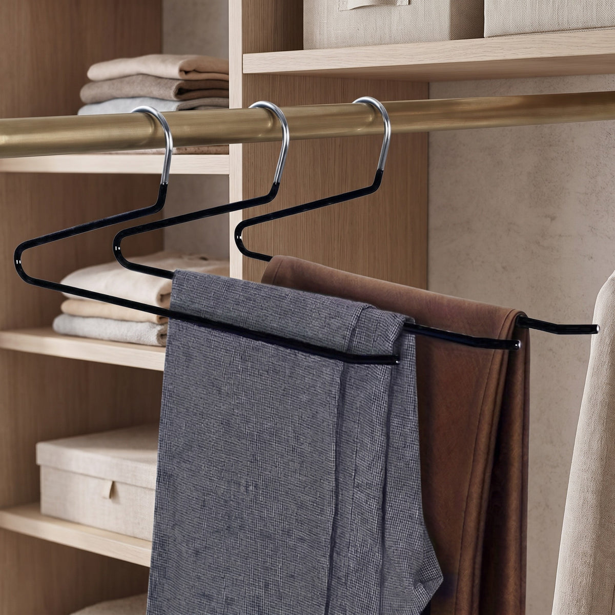Three black Z shape pants hangers holding trousers in a closet