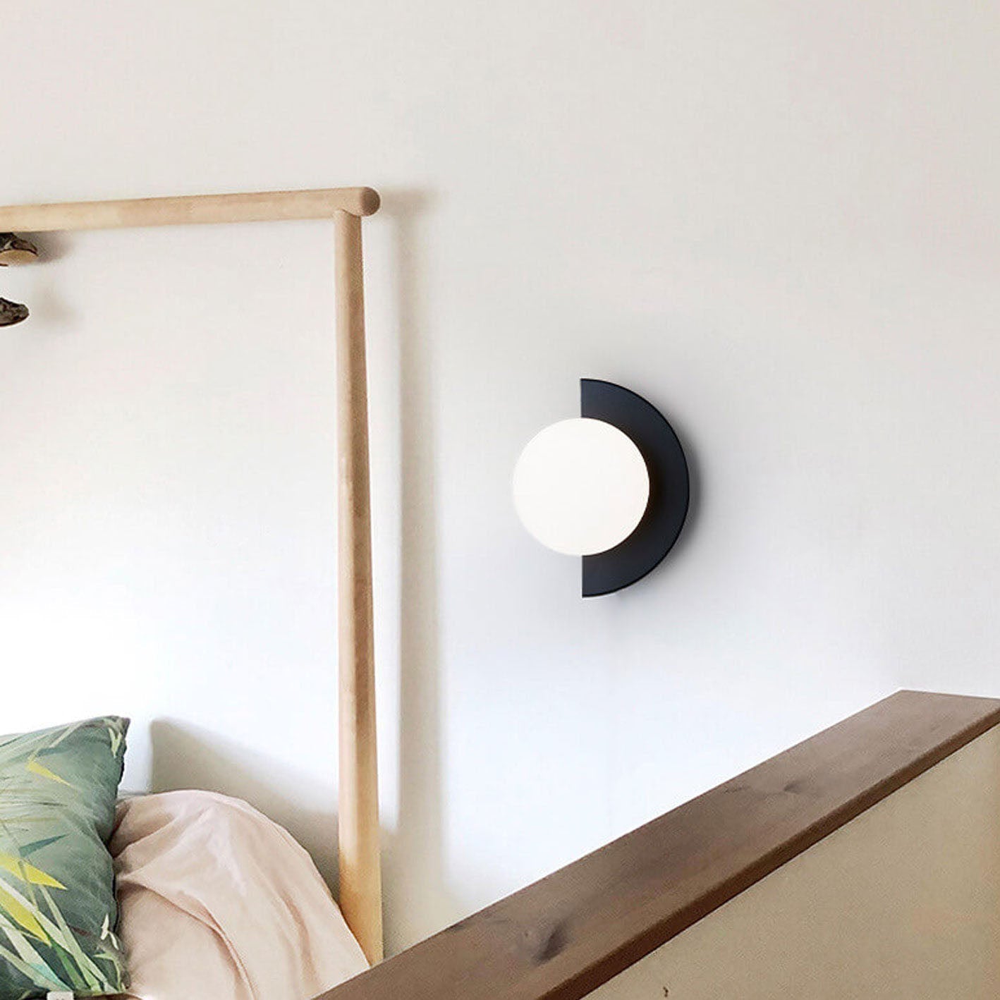 Glass wall sconce with black iron frame and spherical glass shade
