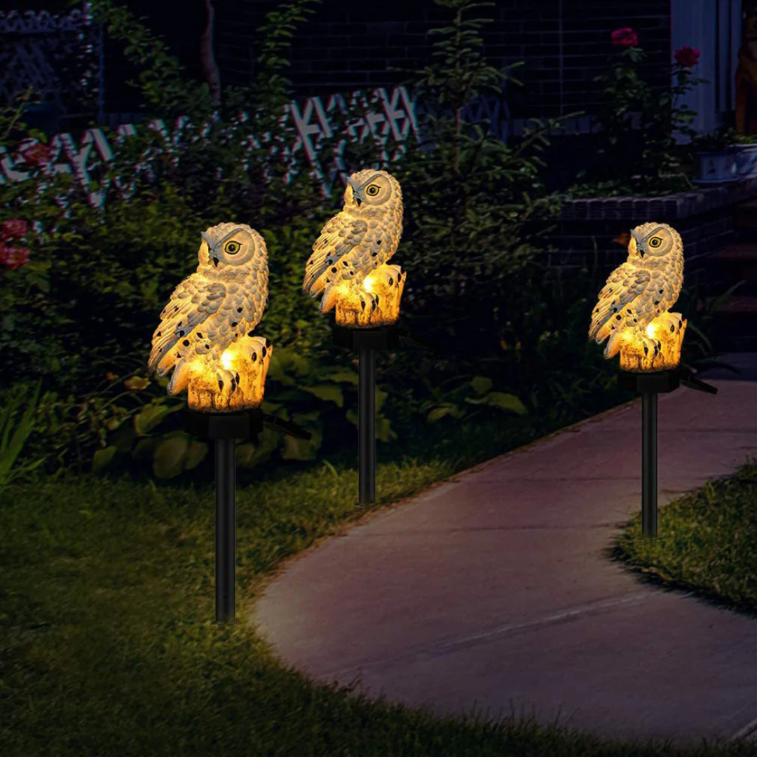 Two solar owl lights lining a garden path at dusk