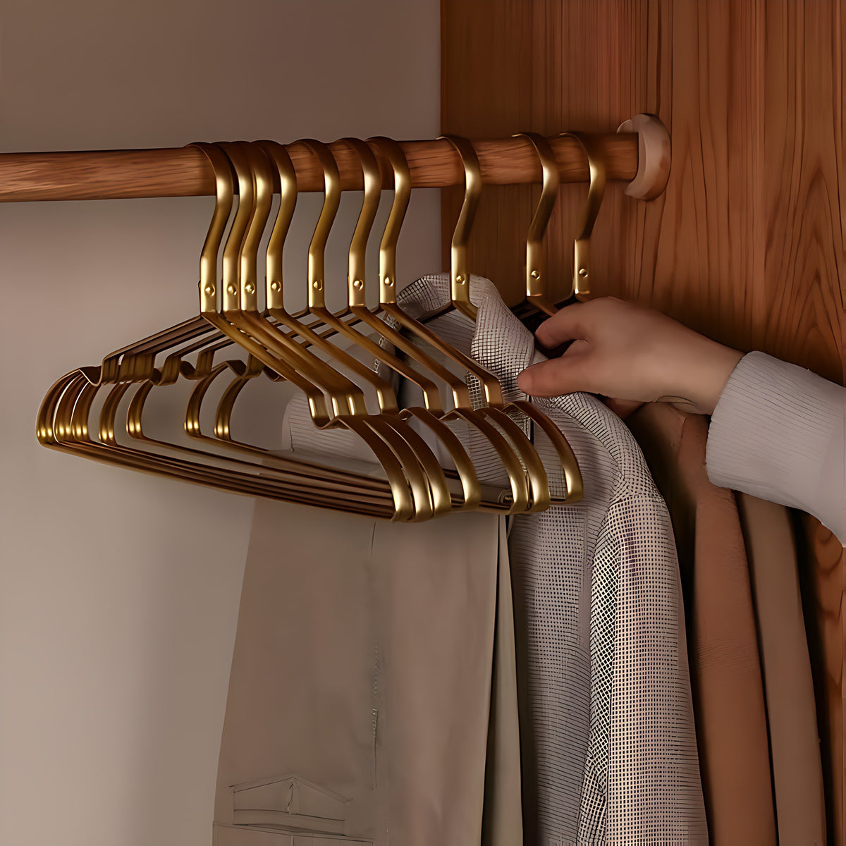 Hand sliding a coat off a gold aluminum hanger