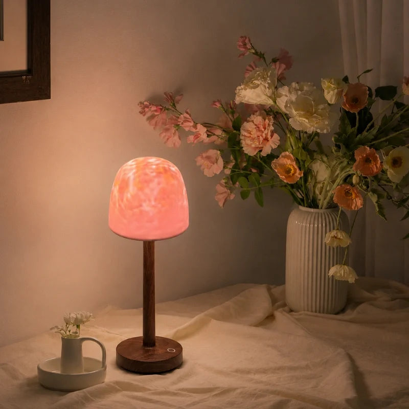 Arvika lamp glowing pink beside a vase of flowers