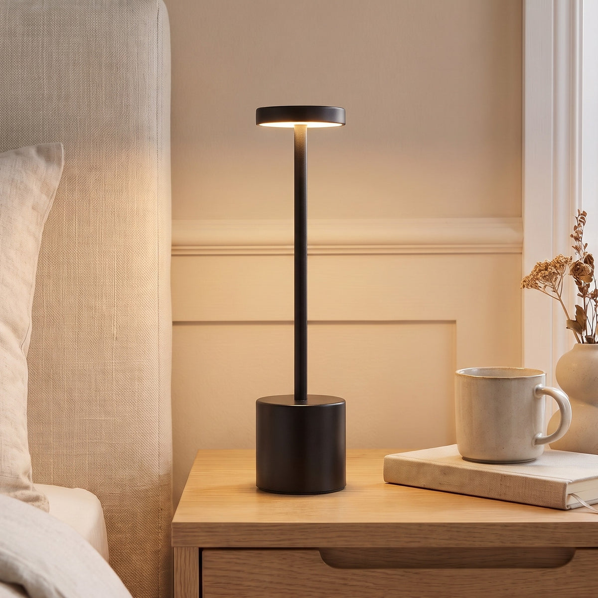 Black Asta cordless table lamp lit on a bedside table