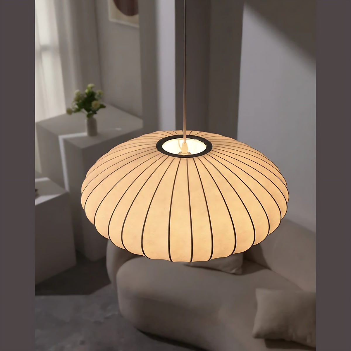 Britt pendant light, ribbed fabric saucer glowing over a curved sofa