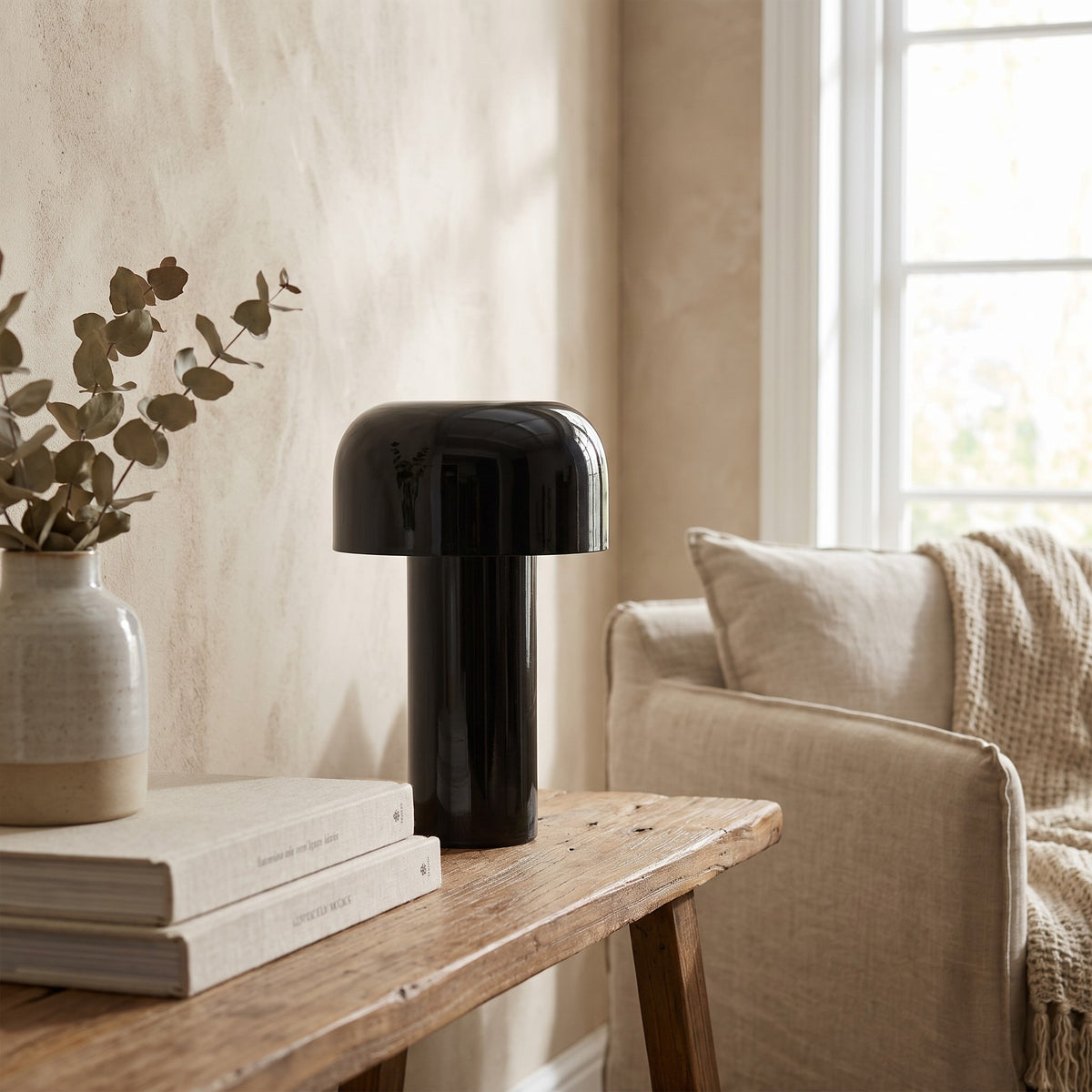 Britta dome table lamp in black on a console beside books