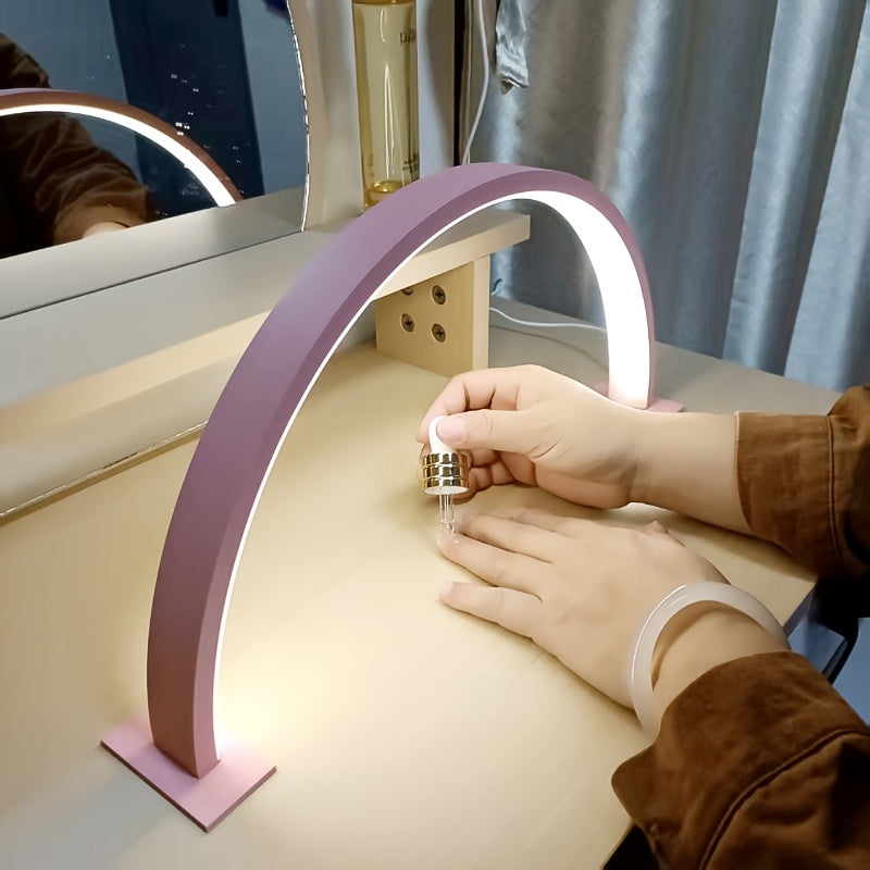 Pink arc desk lamp lighting a manicure on a wooden table