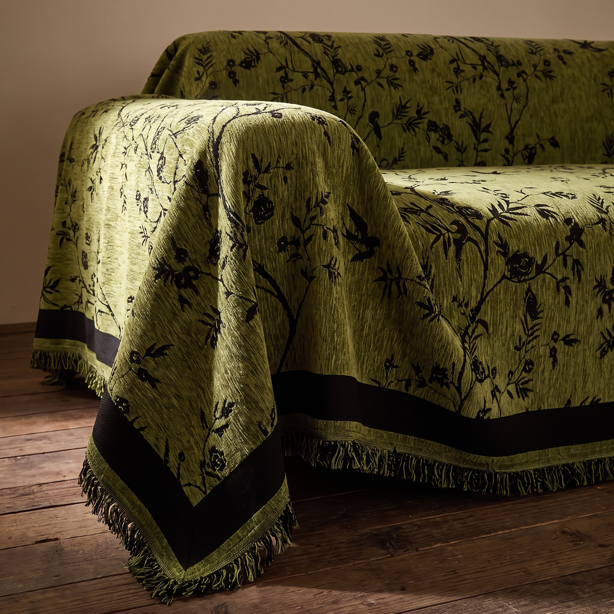 Close view of the floral and bird jacquard, border band and tassels of the chenille sofa cover