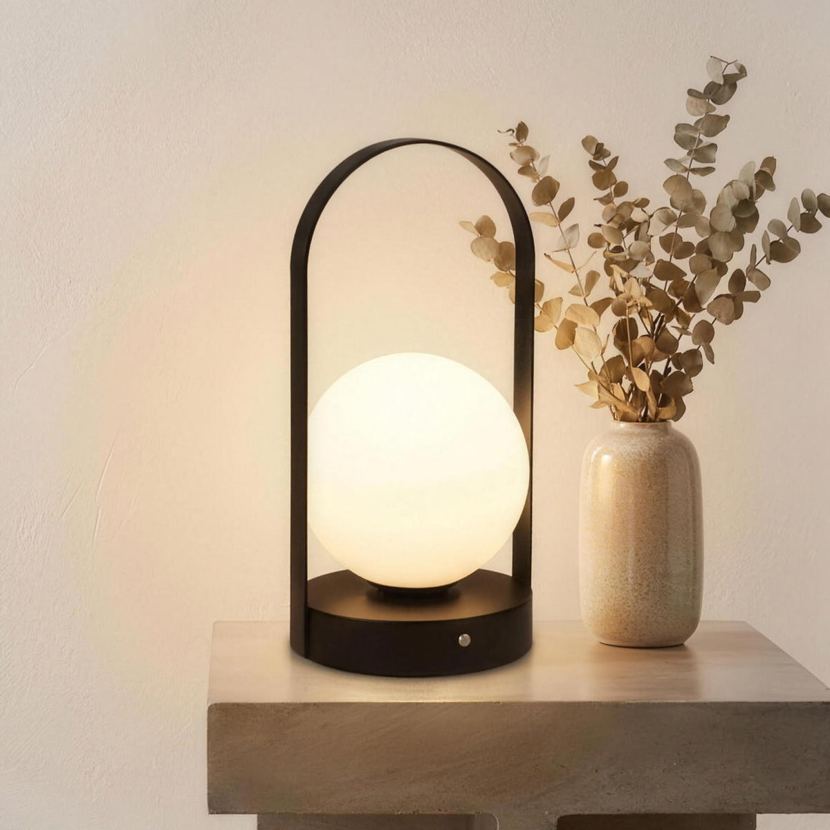 Black Disa rechargeable table lamp lit on a stone side table