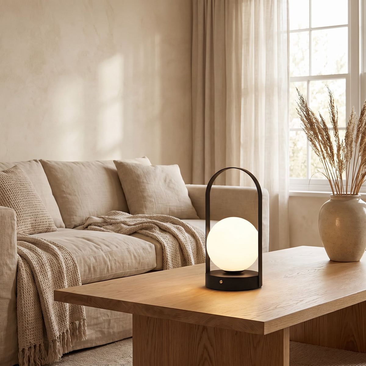 Black Disa rechargeable table lamp lit on a coffee table by a sofa