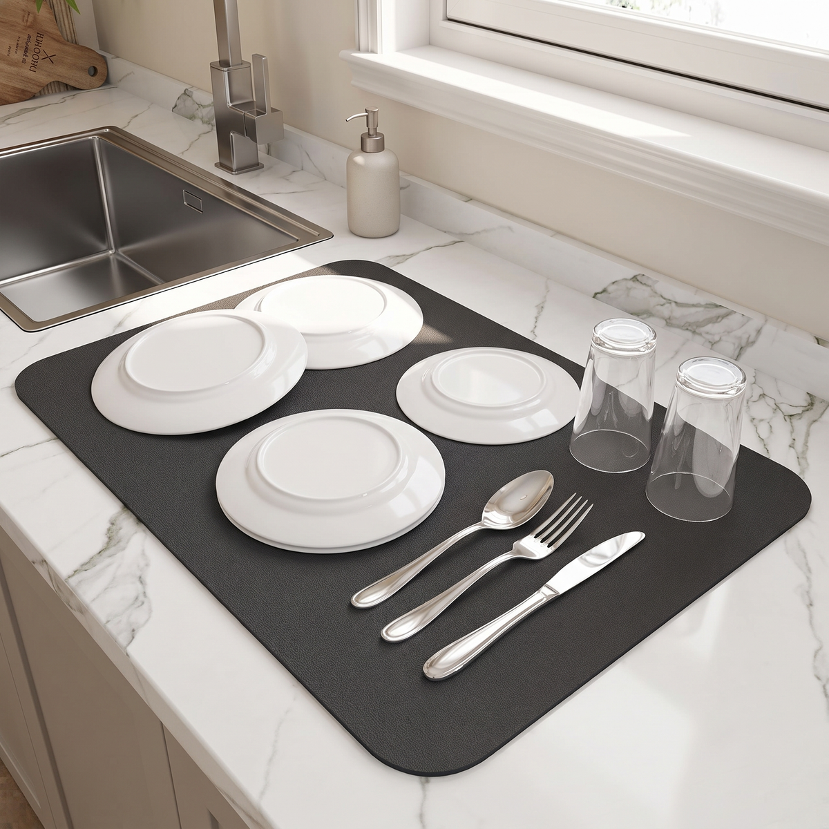 Black dish drying mat with plates and glasses beside a sink