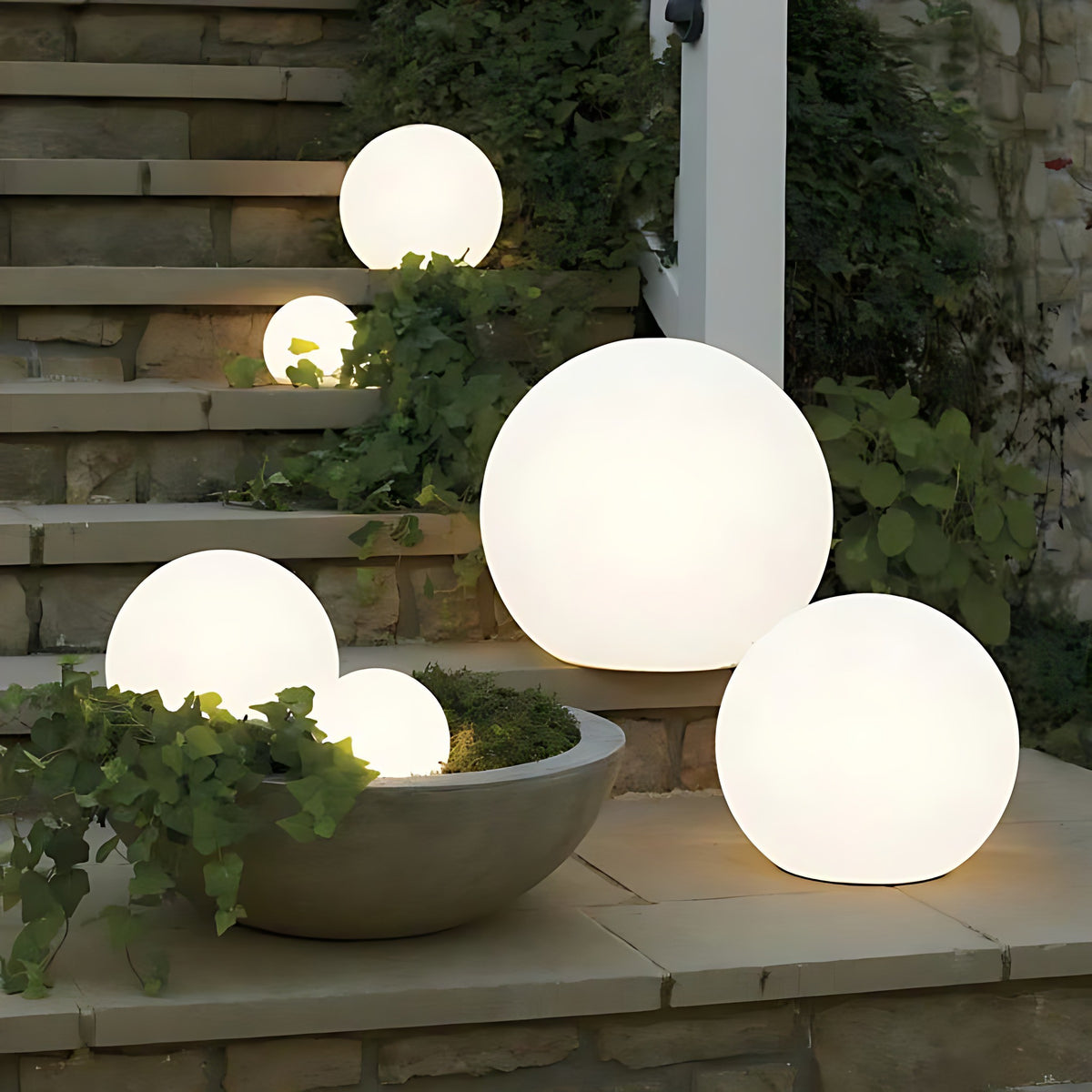 Ellen globe garden lights in several sizes lit on garden steps