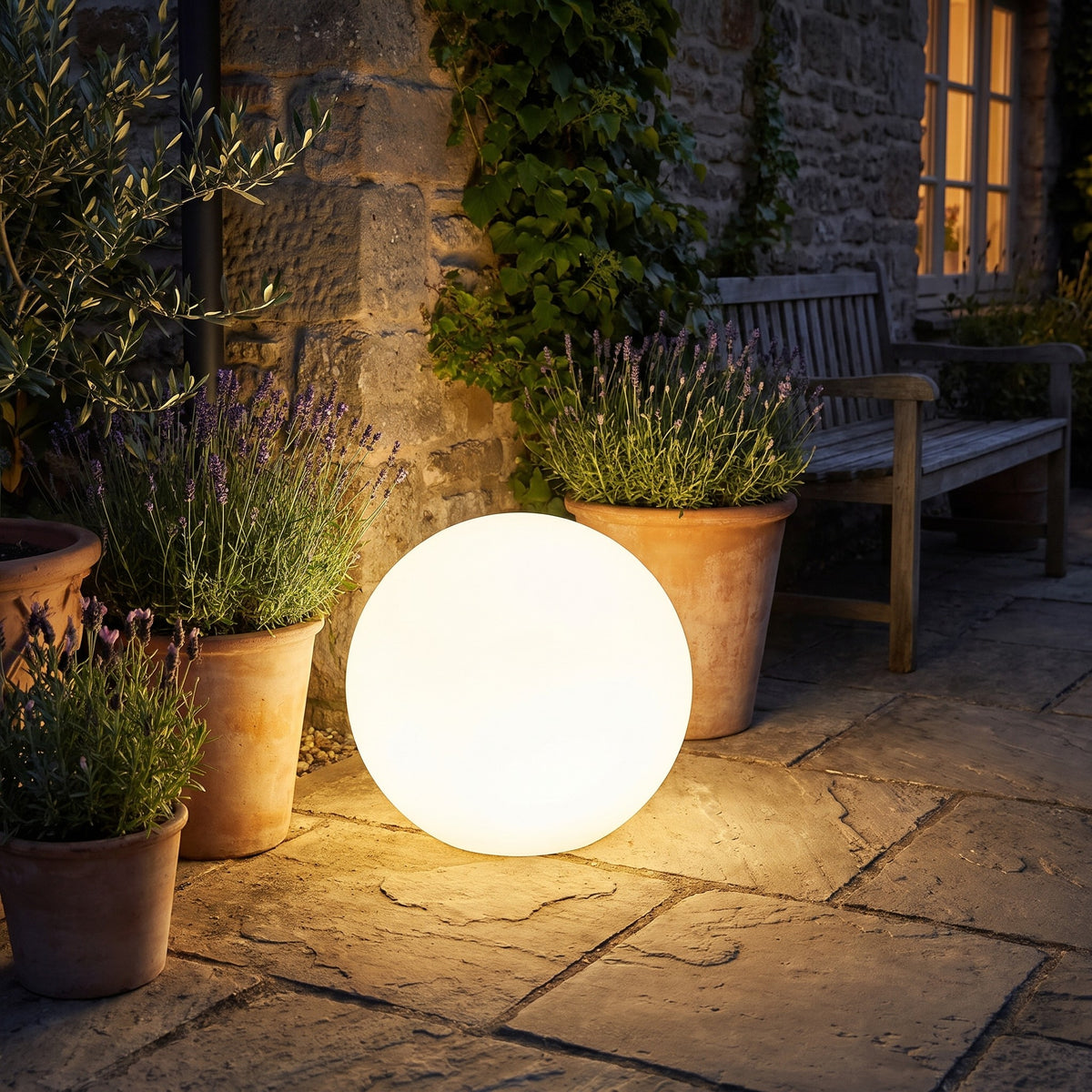 Ellen globe garden light glowing on a terrace beside potted lavender