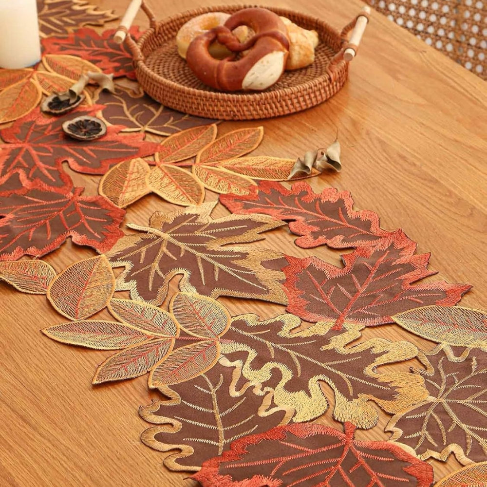 Embroidered leaf runner on a wood table with a basket of bread