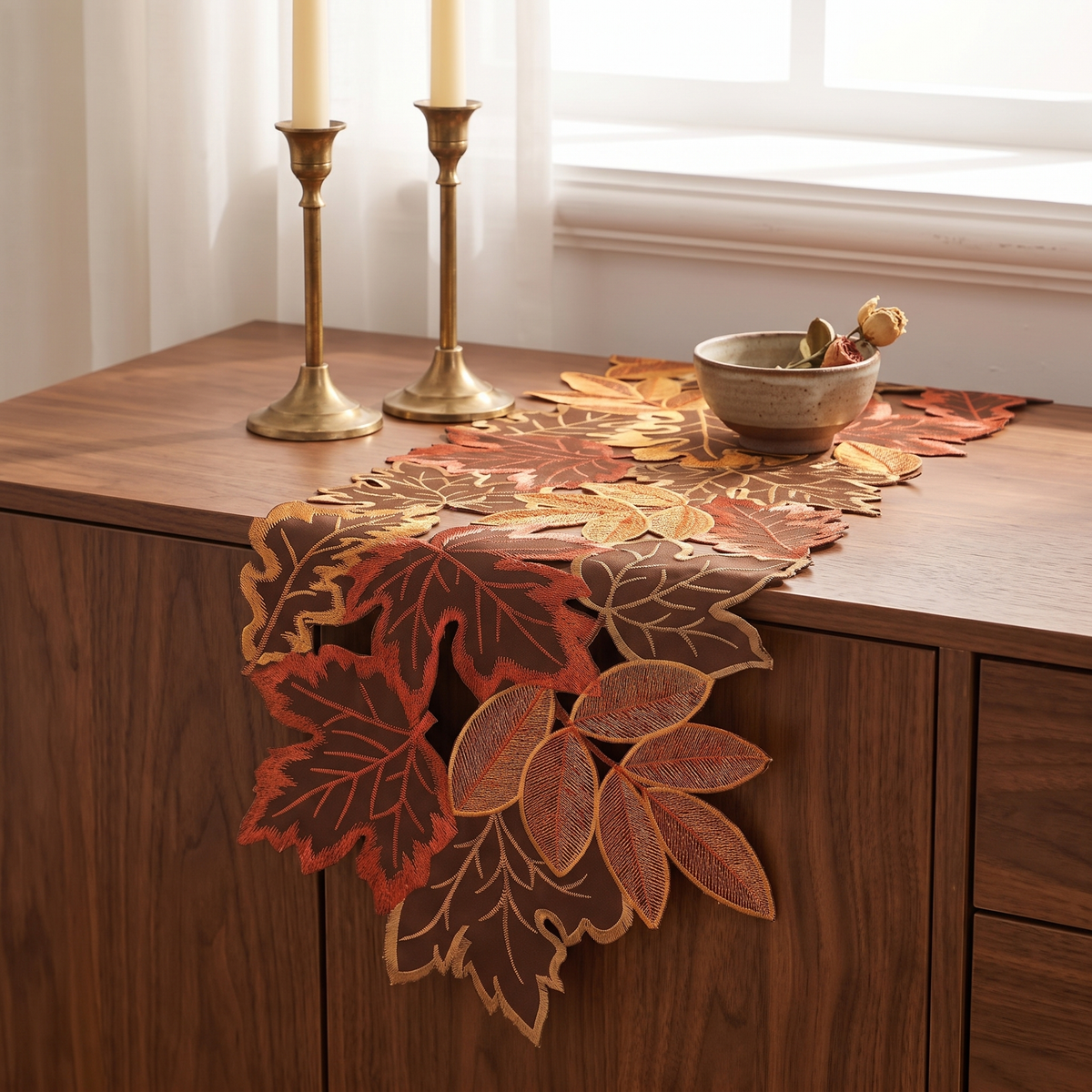 Embroidered maple leaf runner on a walnut sideboard with brass candlesticks