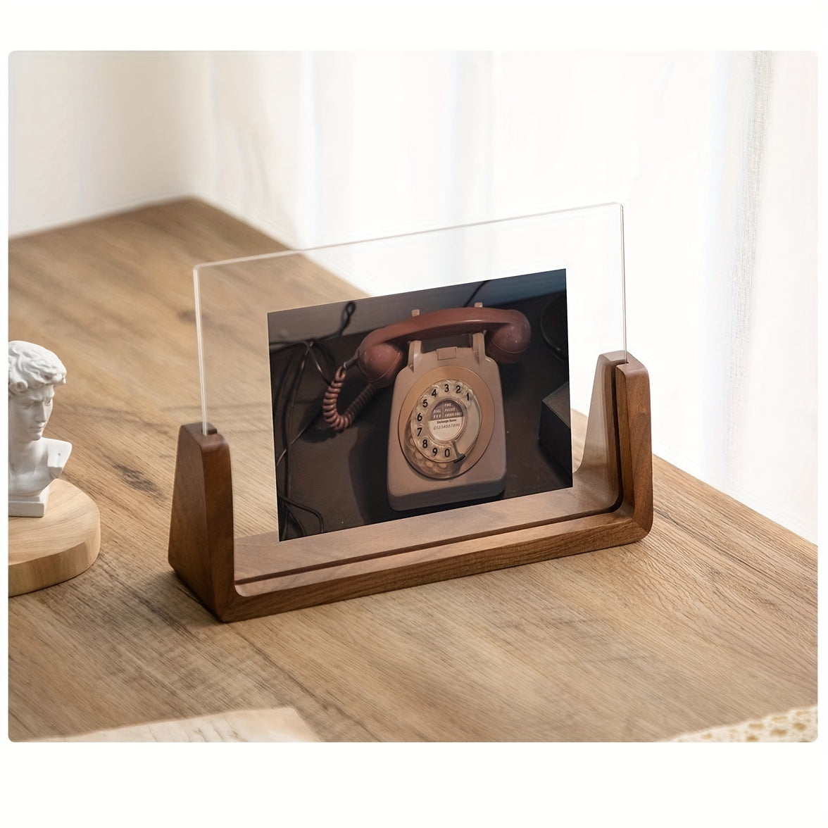 Fana walnut U frame holding a photo of a rotary phone on a wooden desk