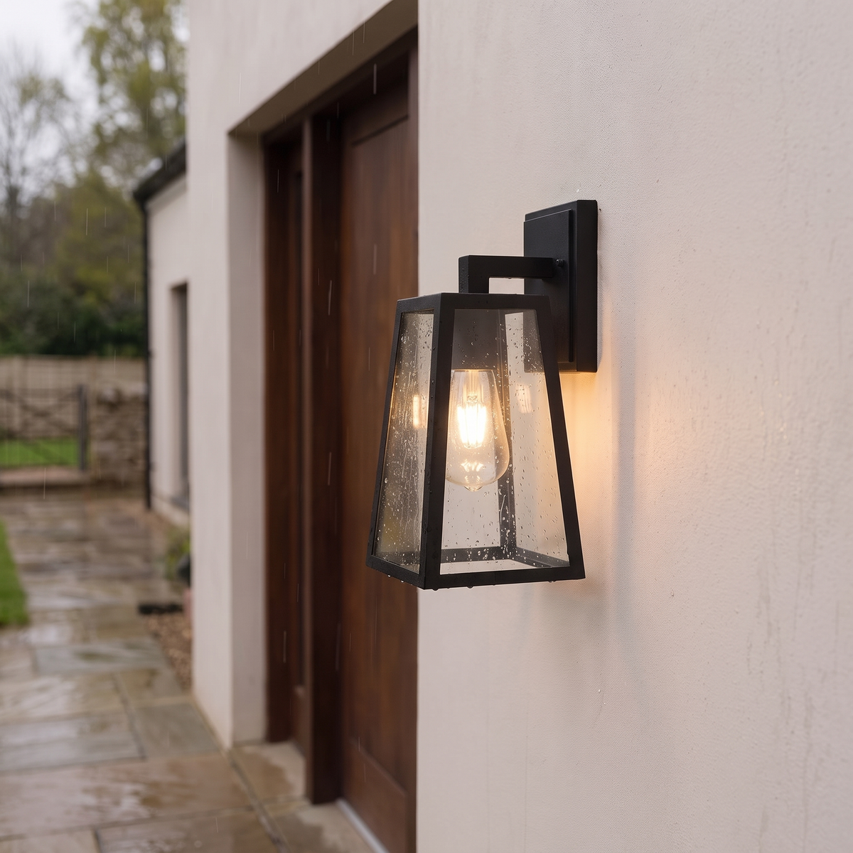 Fjell lantern lit on an exterior wall with raindrops on the panels