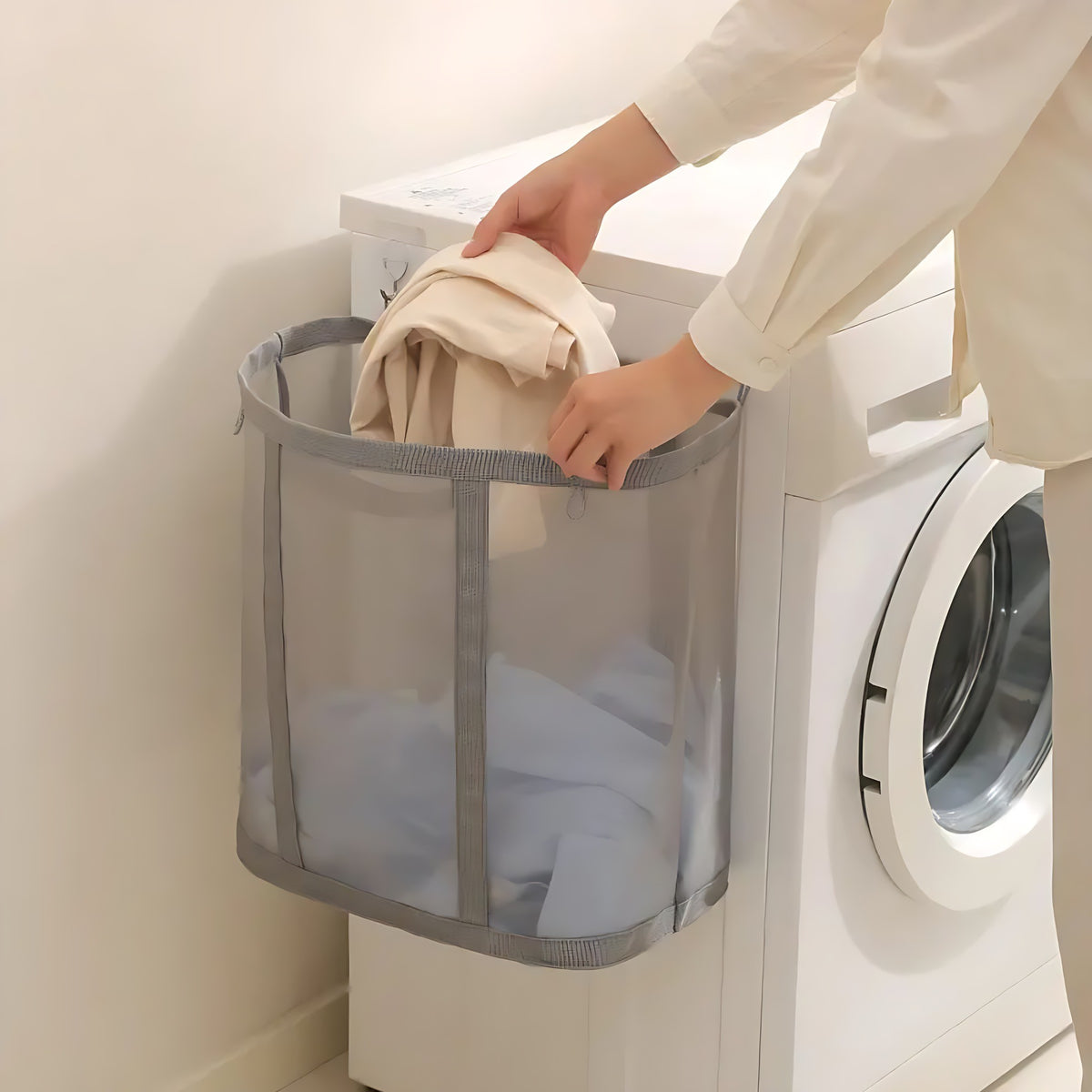Clothes dropped into a gray mesh laundry basket hanging by a washer