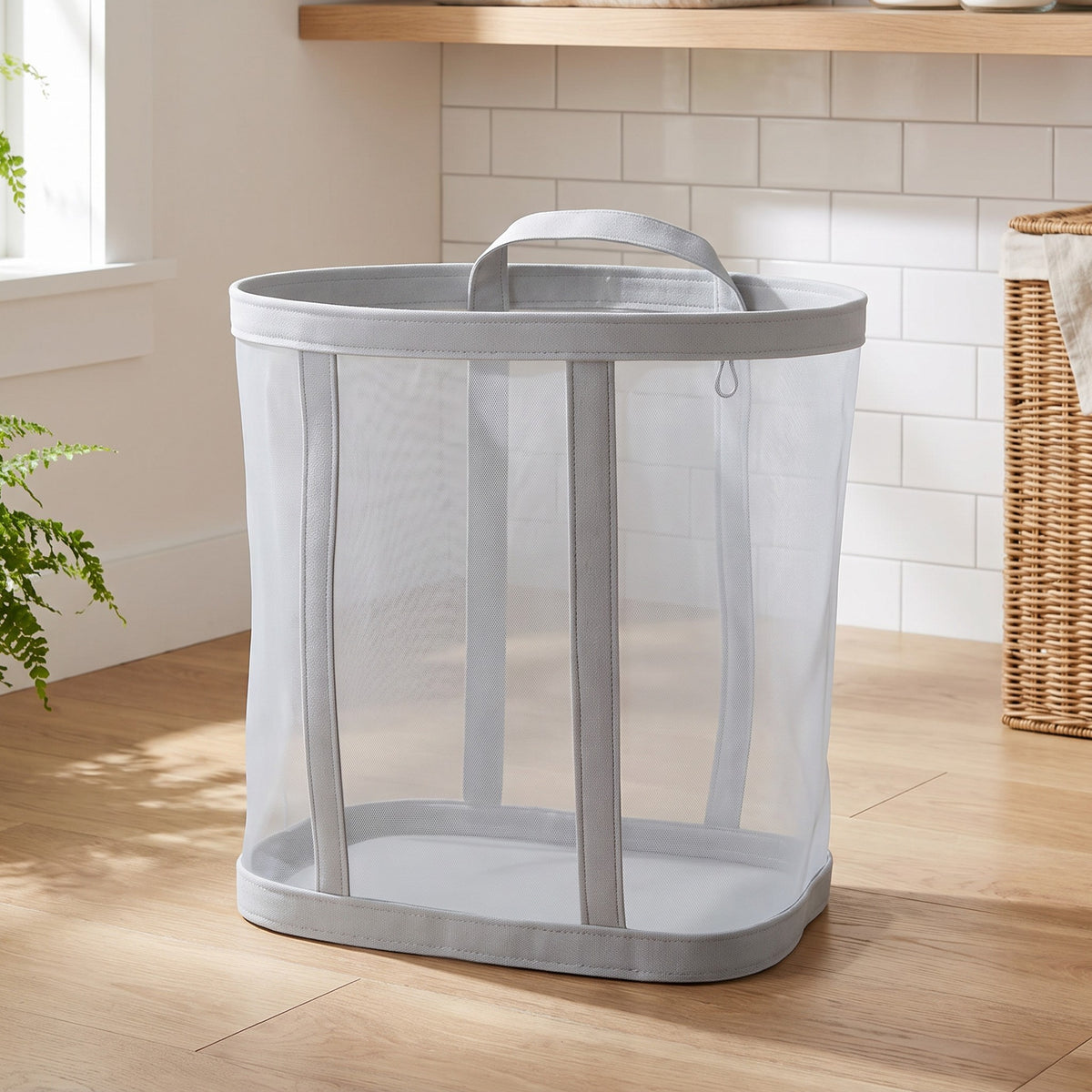 Gray mesh laundry basket standing on a wood floor in a laundry room