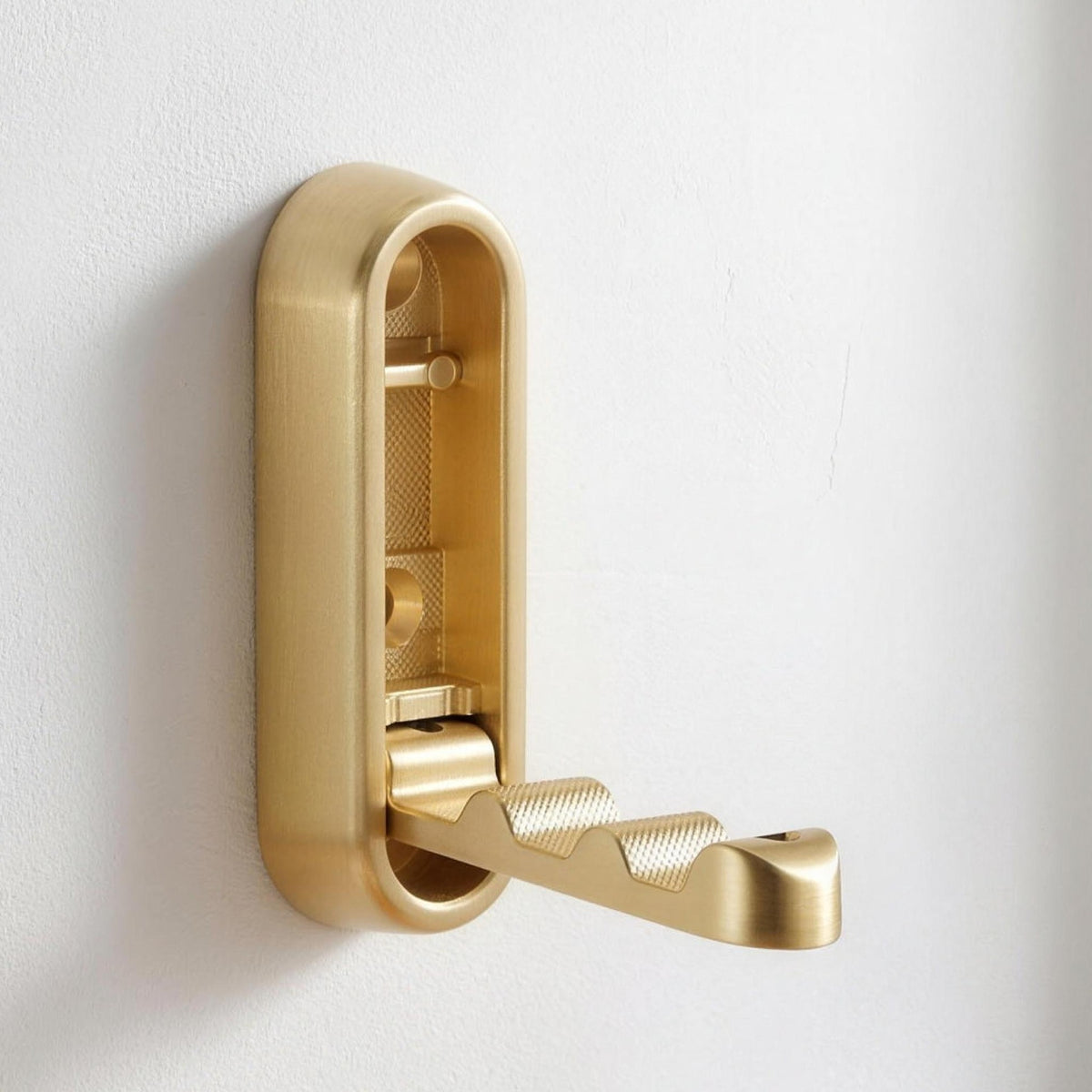 Gold folding wall hook opened out on a white wall