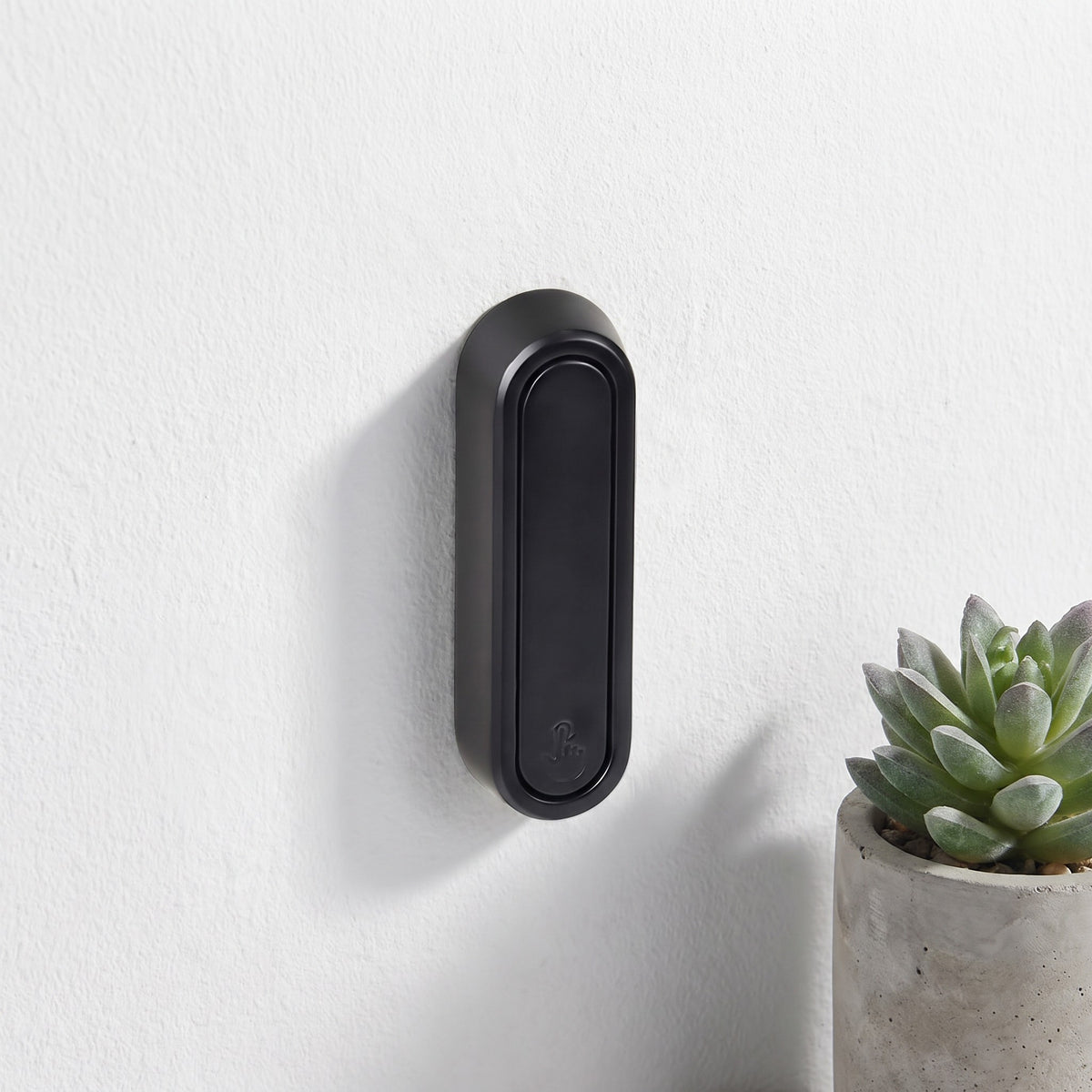 Black folding wall hook on a bathroom wall beside a round mirror