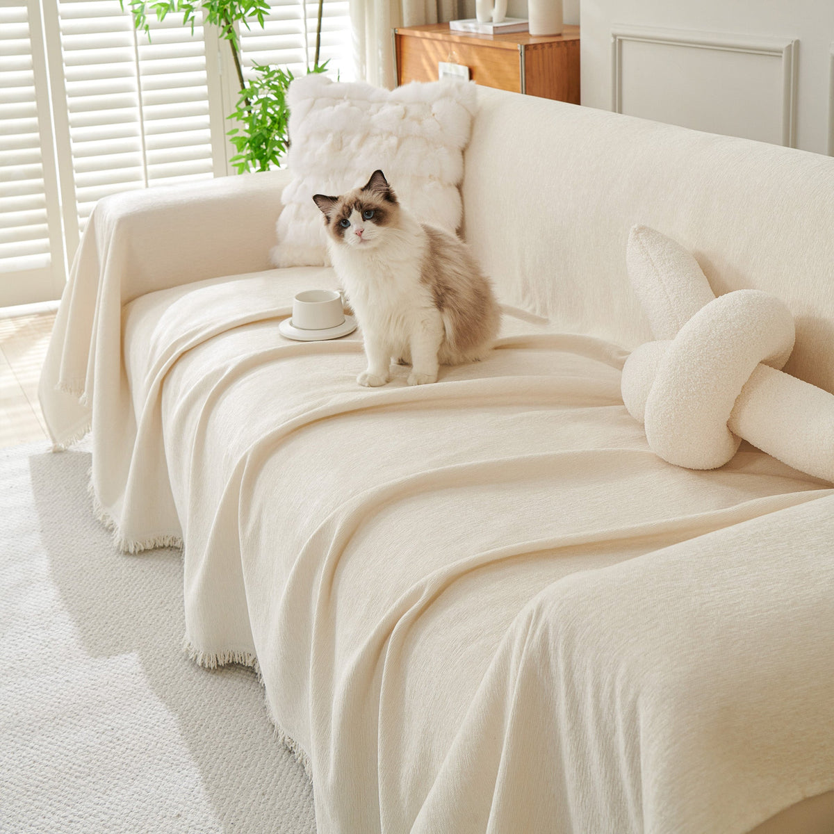 Cat on a cream woven cover draped over a sofa