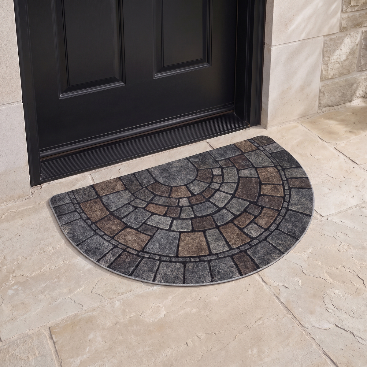 Half round mosaic door mat against the threshold of a black front door