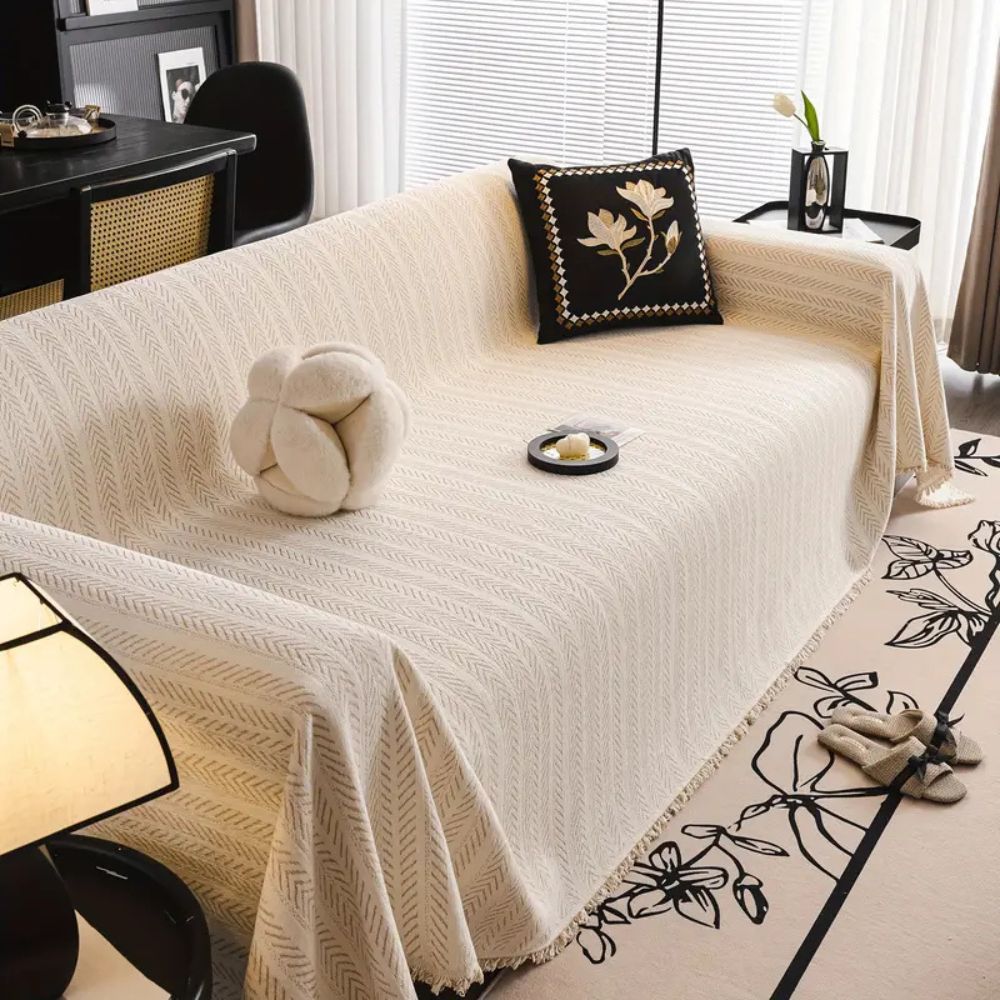 Beige herringbone chenille cover draped over a whole sofa to the floor in a living room