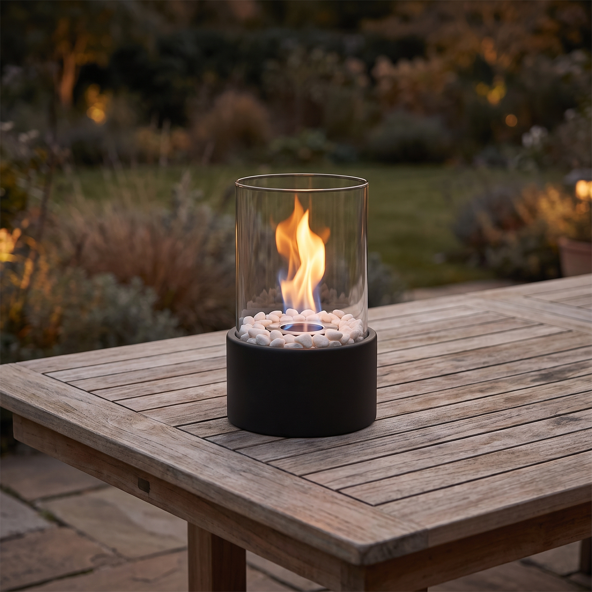 Horten fire lamp lit on an outdoor teak table at dusk
