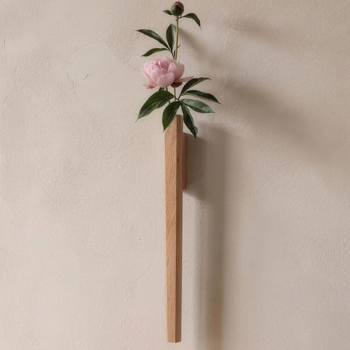 Idun beech wall vase holding a peony above a console table