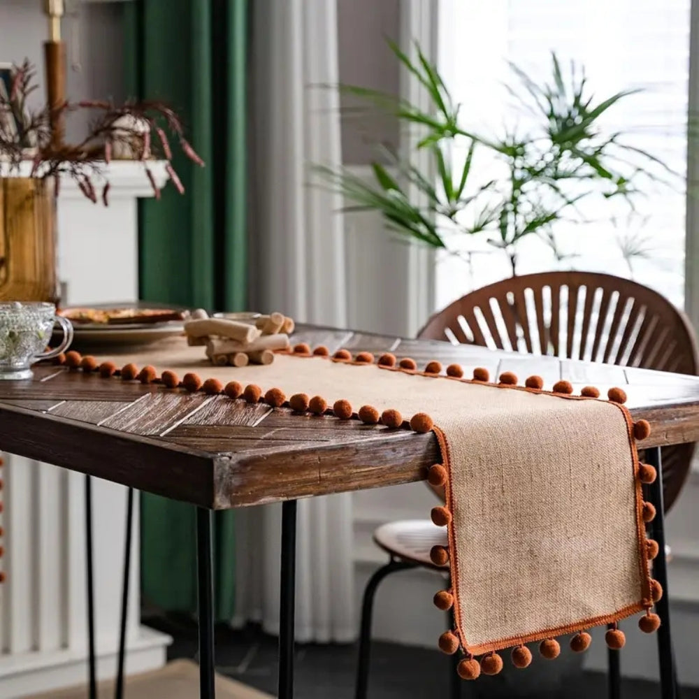 Jute pom pom runner on a dining table by a window