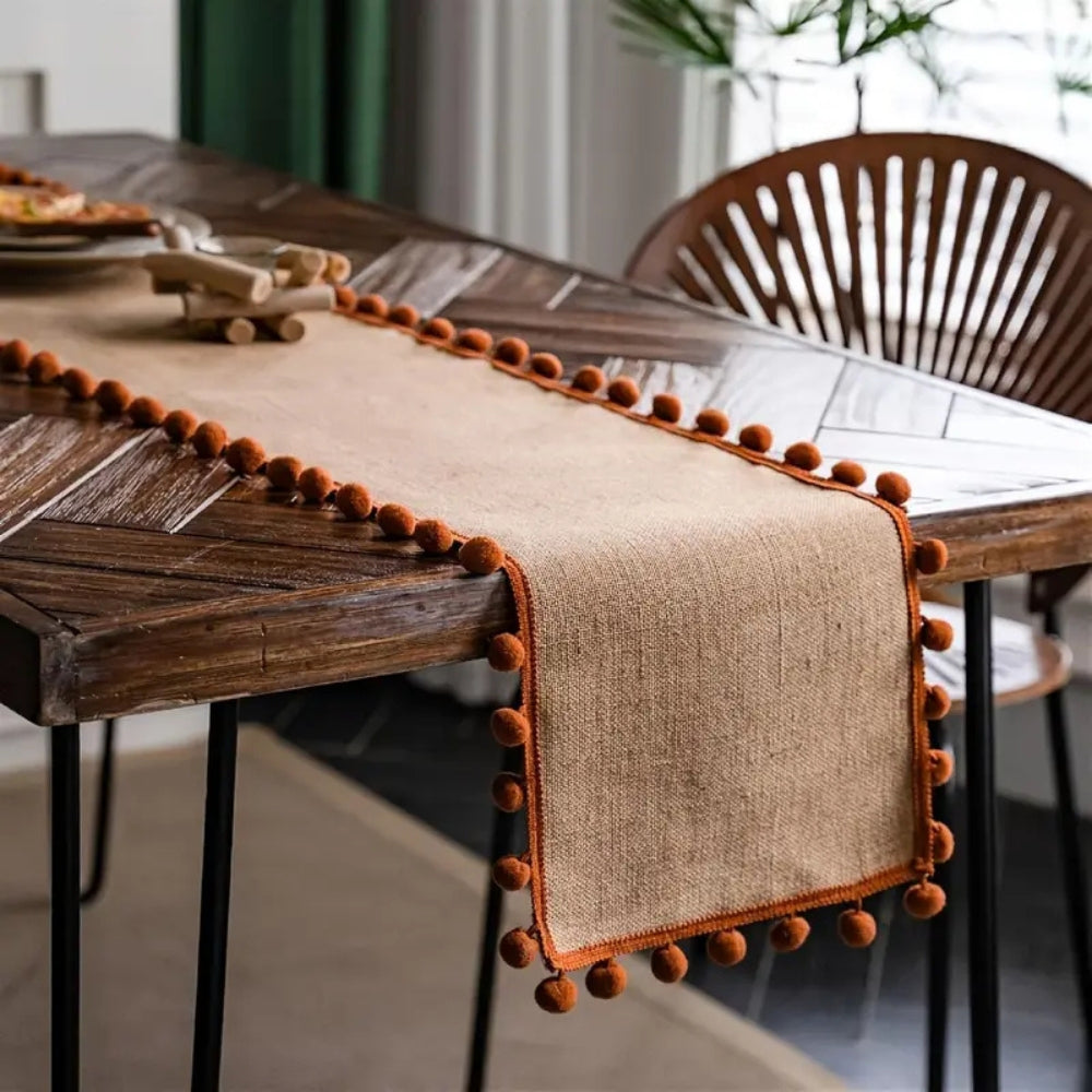 Jute pom pom runner down a wood table with plates