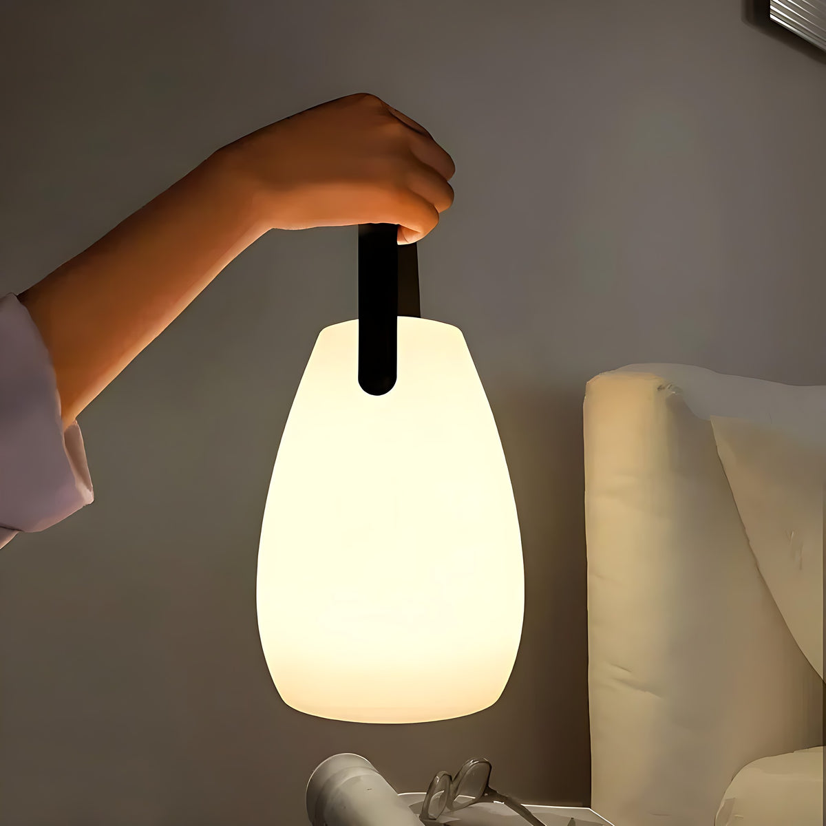 Kari cordless lamp carried by its handle beside a sofa