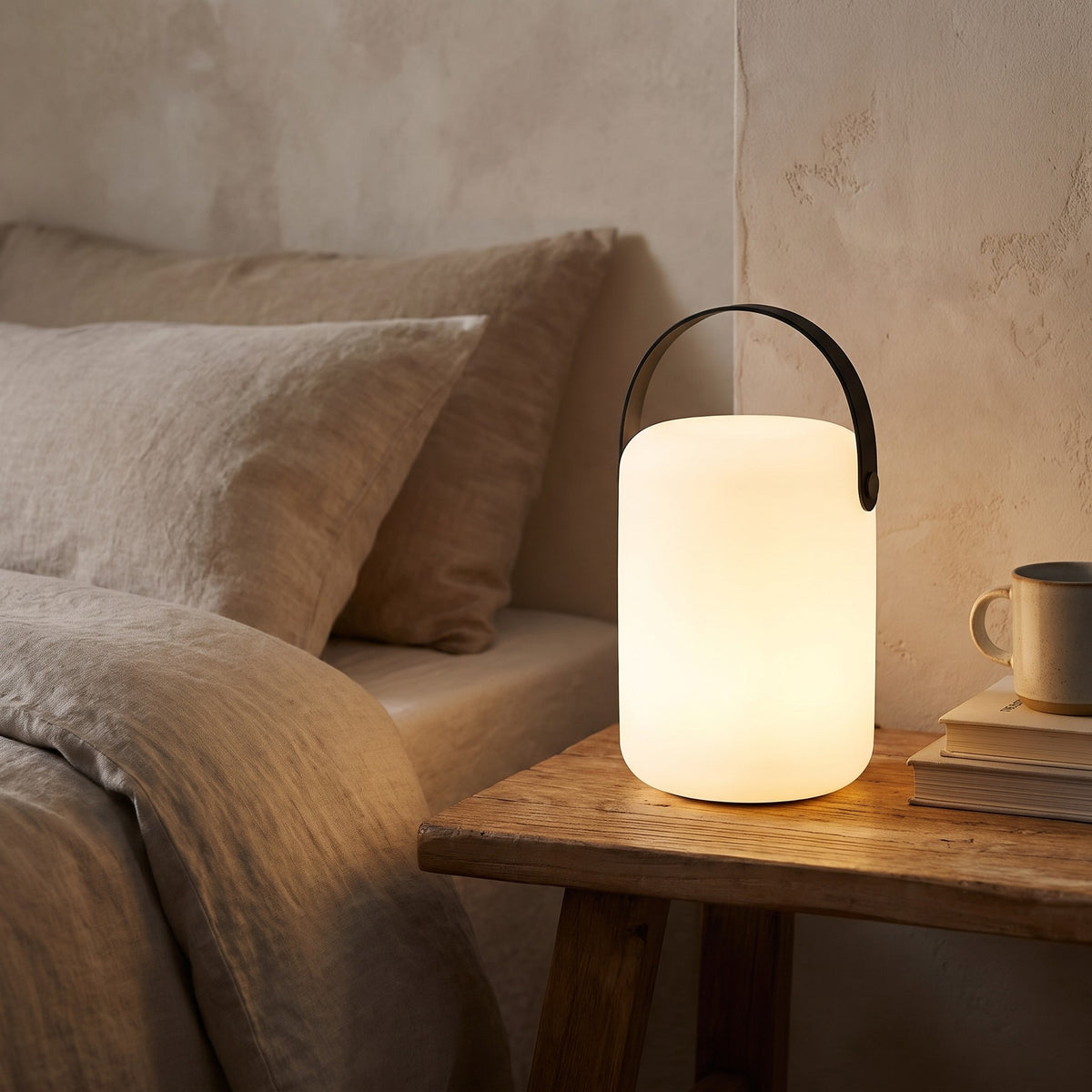 Cylinder Kari cordless lamp glowing on a bedside table