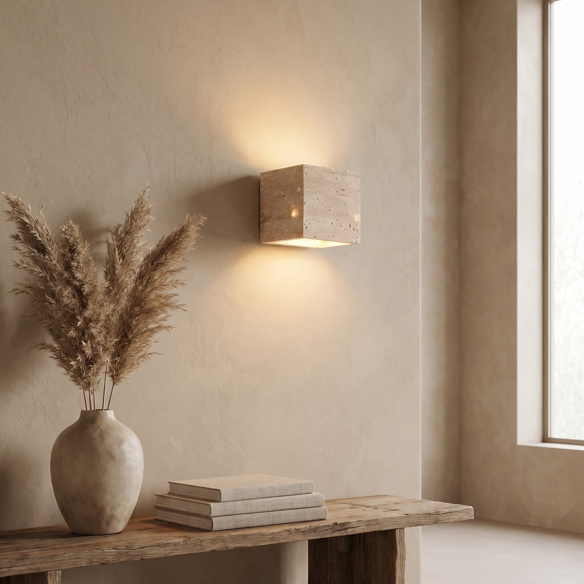 Square Karin travertine wall light lit above a console with pampas grass