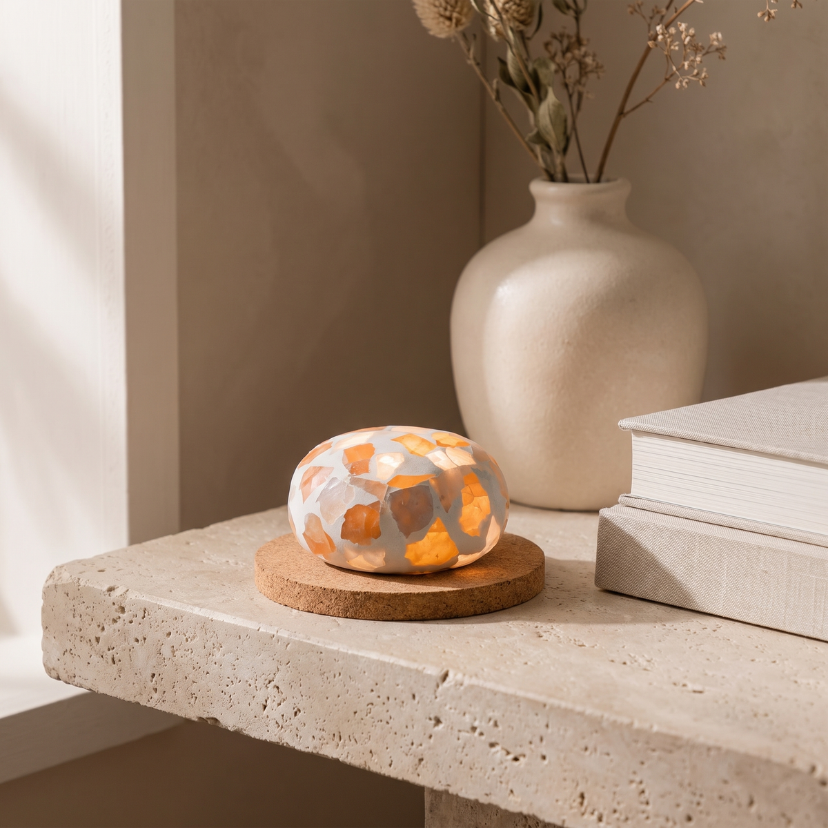 Kvist dome light glowing on its round base on a stone shelf