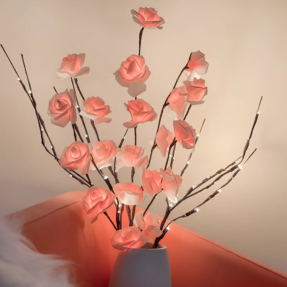 Lighted branches with pink roses beside a sofa