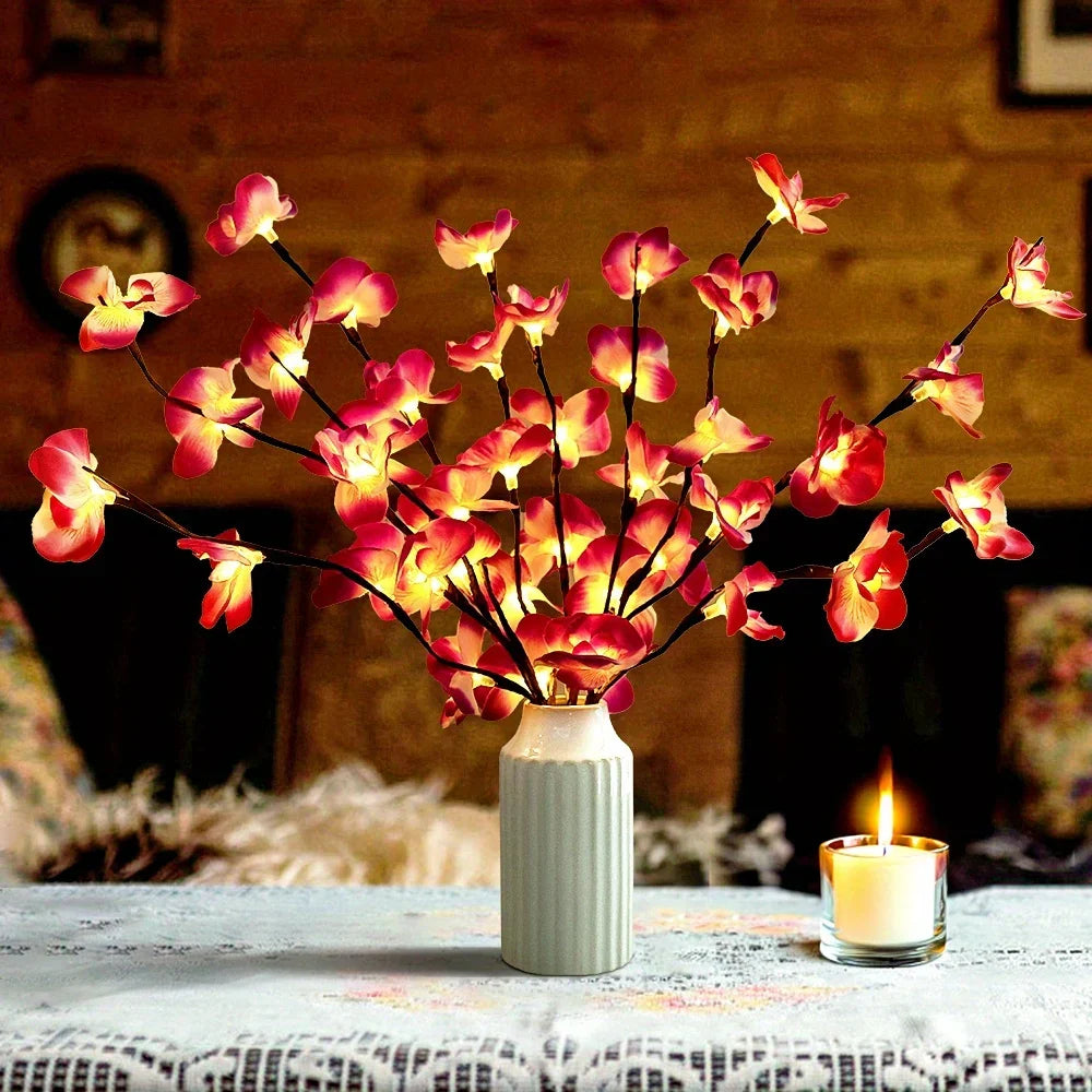 Lighted orchid branches in a vase beside a candle