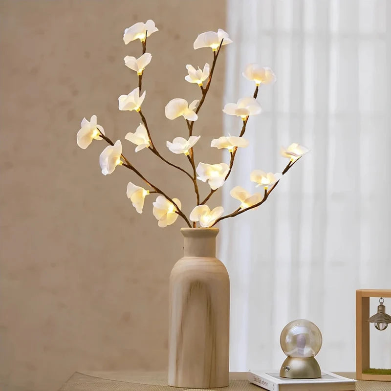 Lighted white orchid branches in a white vase