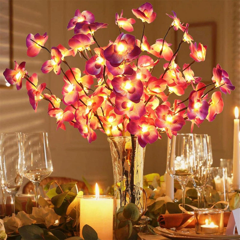 Lighted orchid branches in a glass vase on a dining table
