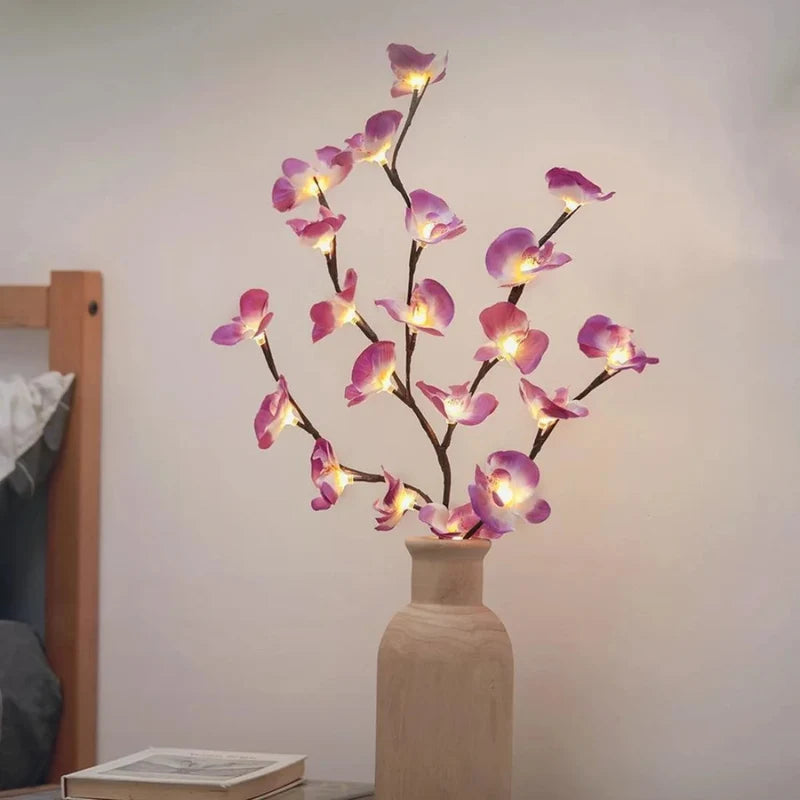 Lighted purple orchid branches in a white vase