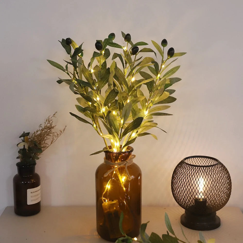 Lighted olive branches in an amber glass vase