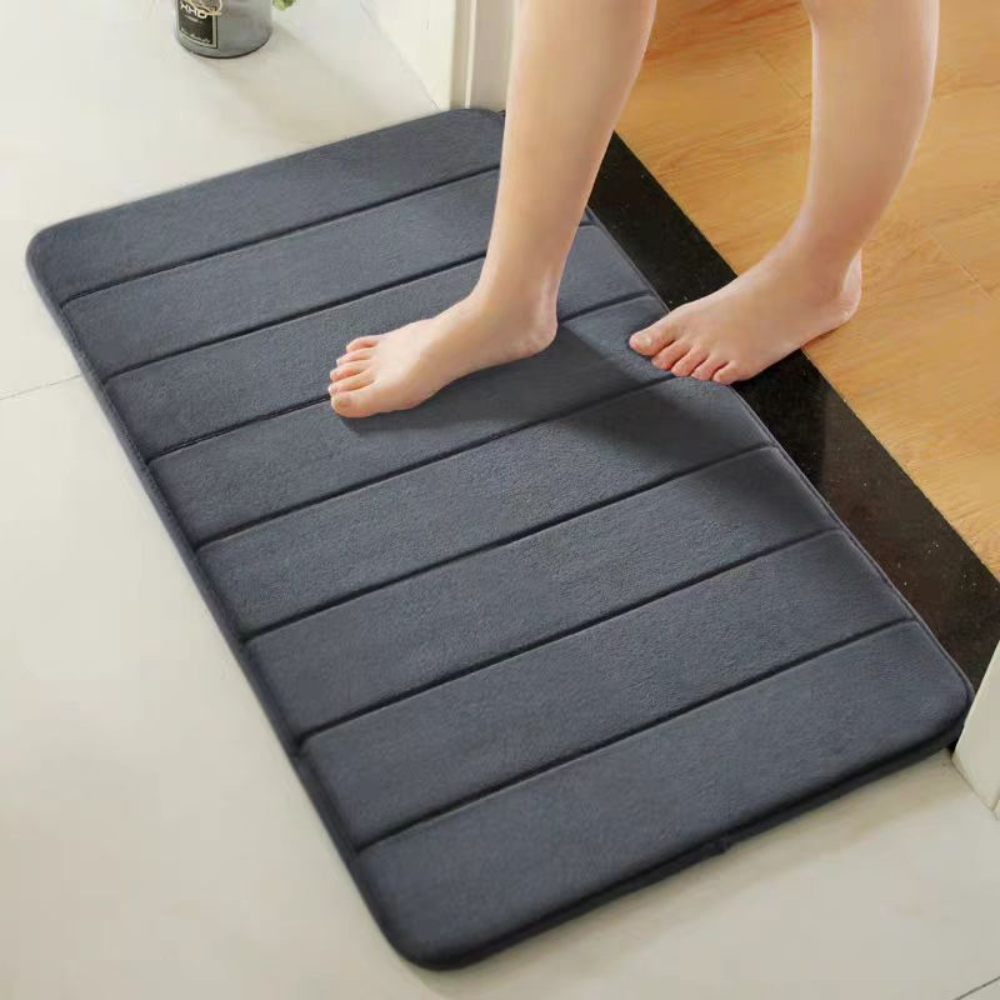 Dark gray microfiber bath mat in front of a shower, bare feet stepping on it