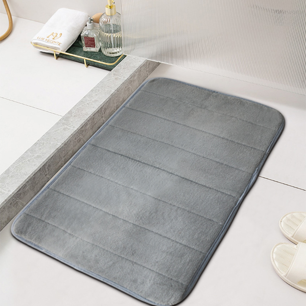 Gray microfiber bath mat with ribbed channels beside a white bathtub