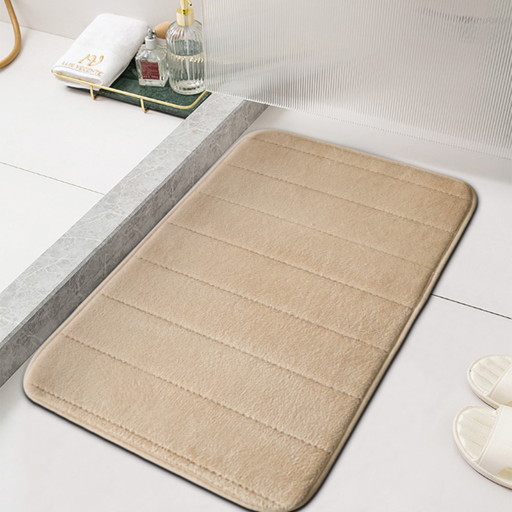 Khaki microfiber bath mat with ribbed channels beside a white bathtub