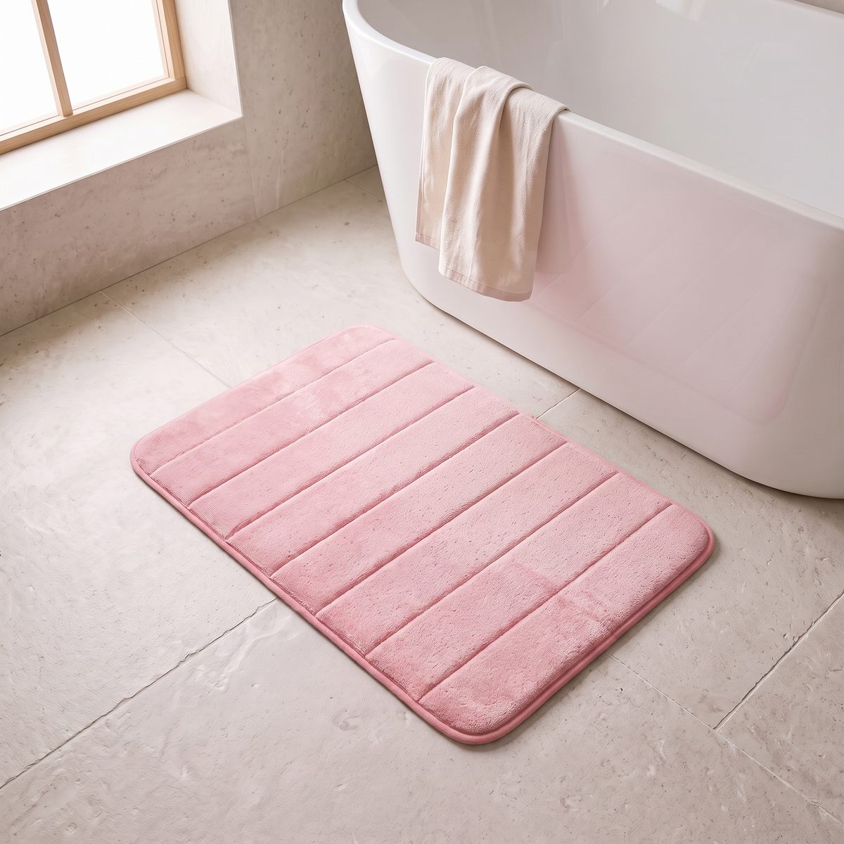 Microfiber bath mat in pink on a stone floor beside a bathtub