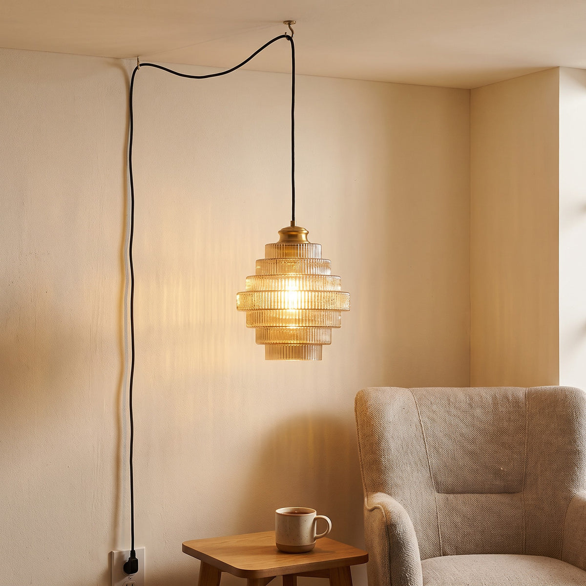 Minna pendant light in amber hanging beside an armchair, a mug of tea on a side table below