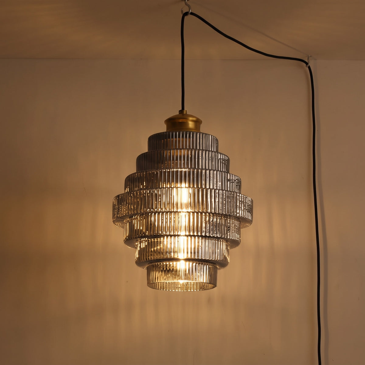 Close view of the Minna pendant light in smoke gray, lit against a plain wall